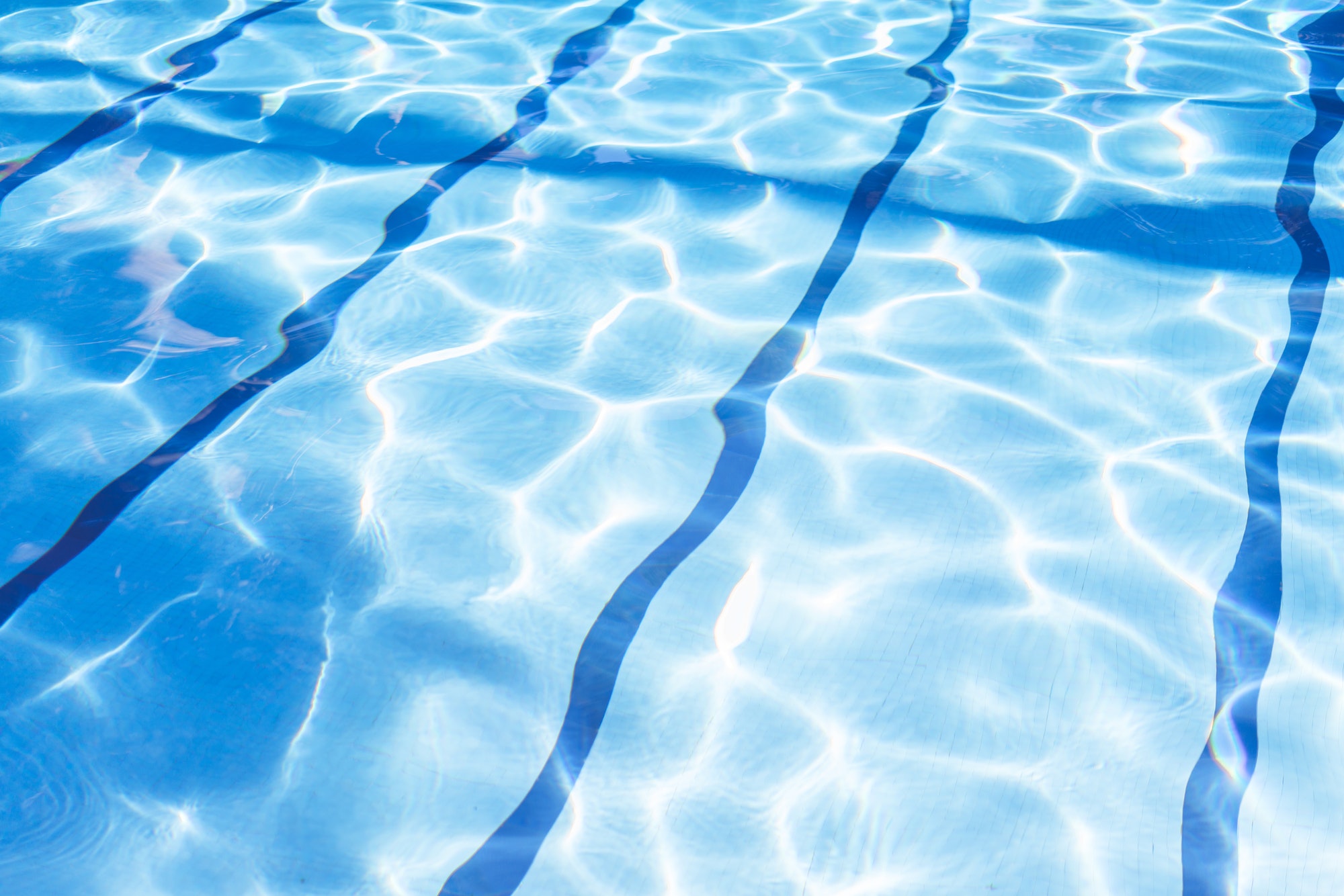 Ripple Water in swimming pool with sun reflection. Summer day at swimming pool.